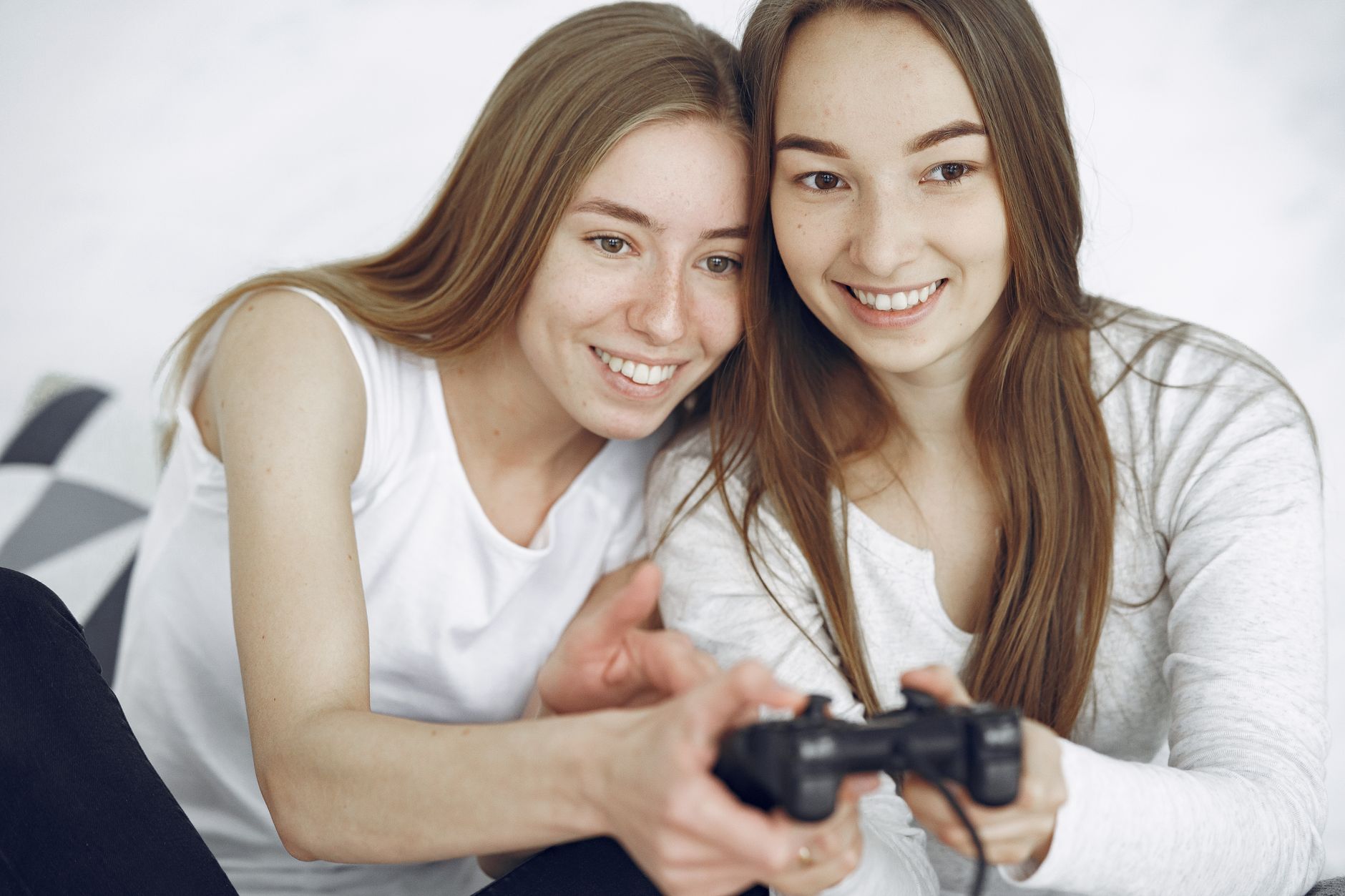 Two young women happily playing a video game indoors, showcasing leisure and connection.