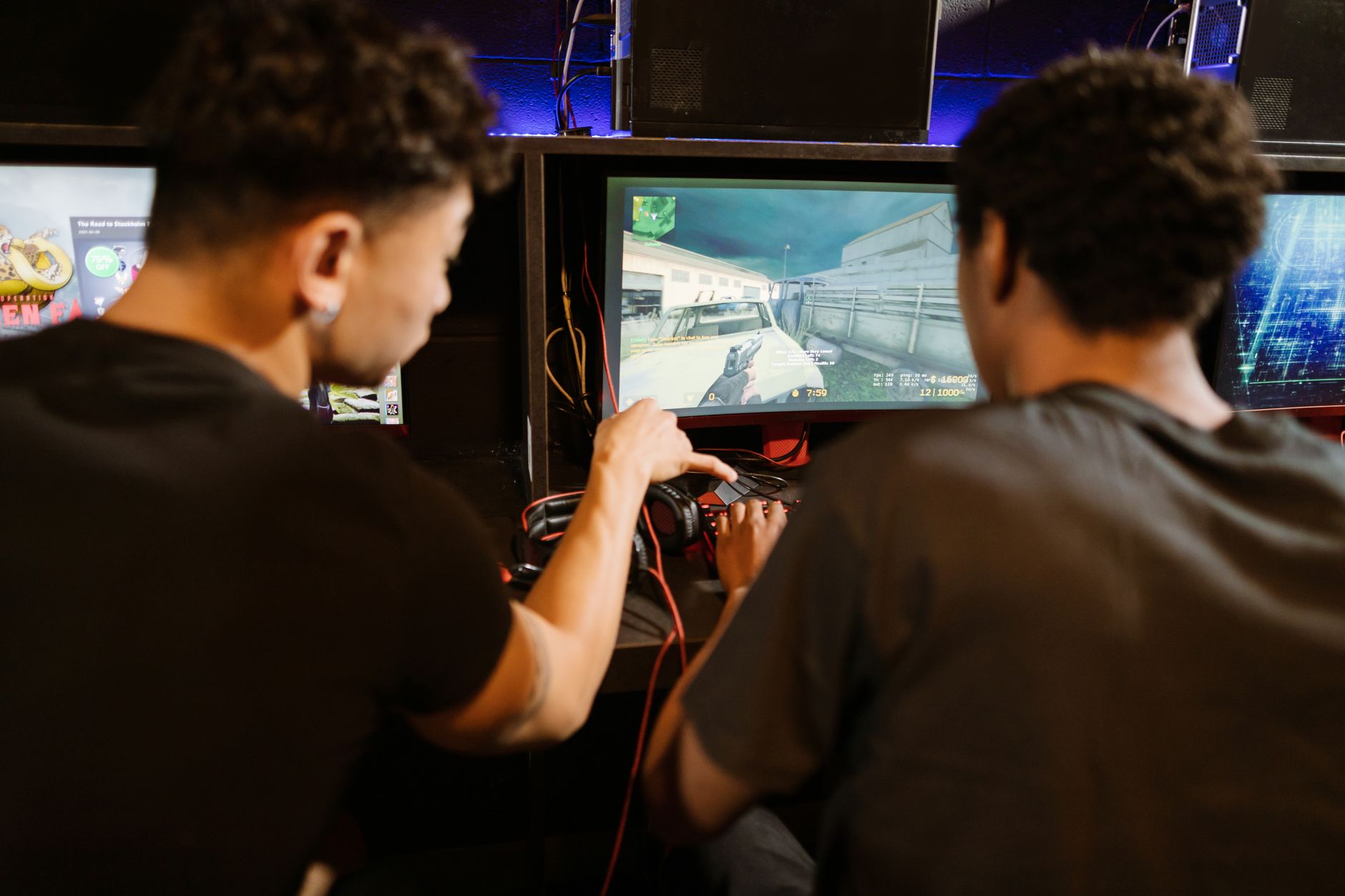 Two young men playing a multiplayer computer game at an arcade with enthusiasm and focus.