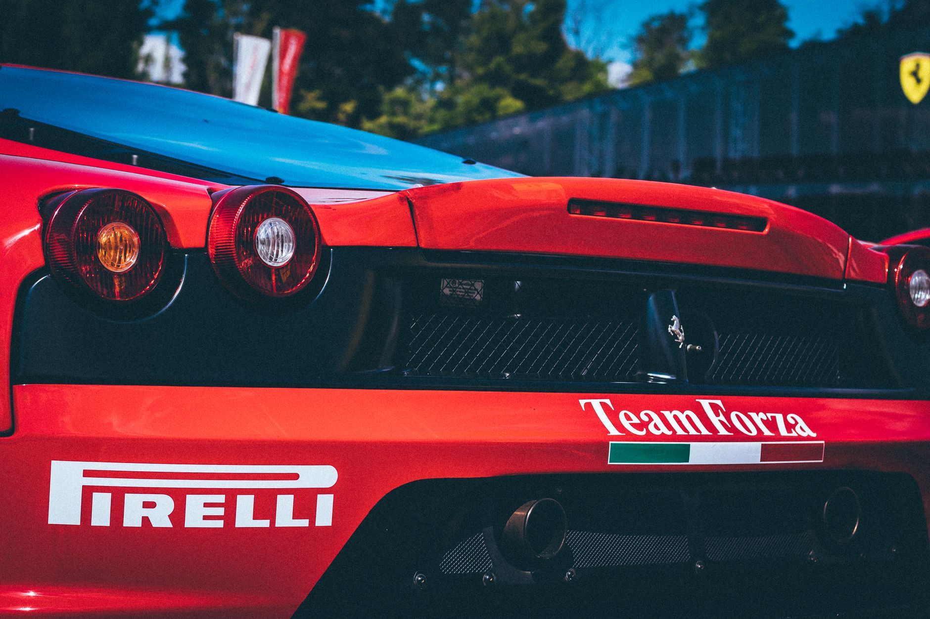 Racing car with Pirelli branding, featuring aerodynamic rear designs. Captured in daylight outdoors.