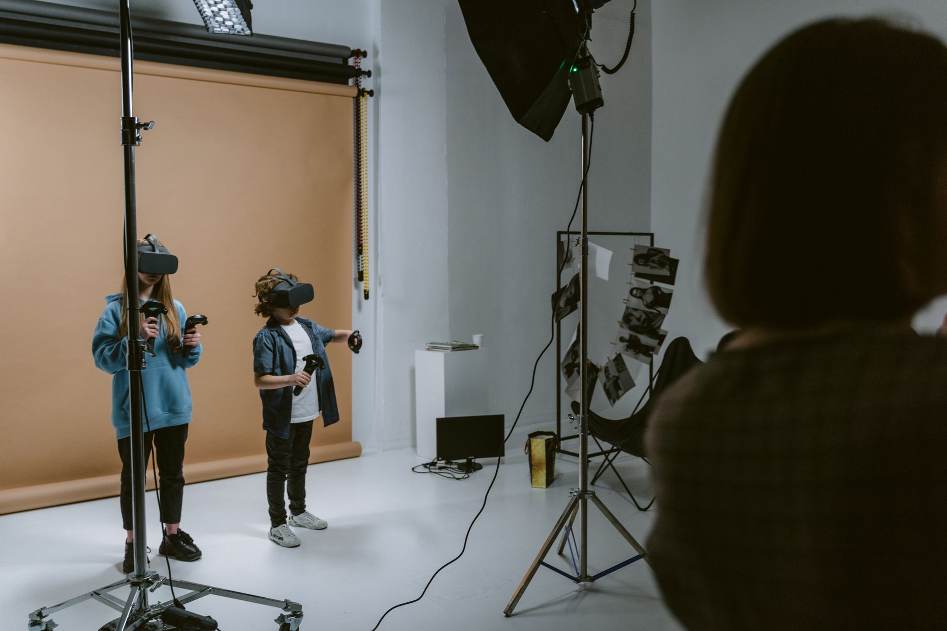 Two kids experience virtual reality gaming in a professional studio setting with VR headsets and controllers.