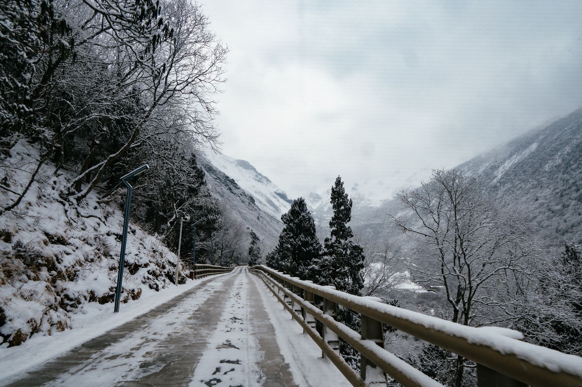 A winding road through a snow-covered mountain forest, offering a serene winter view.