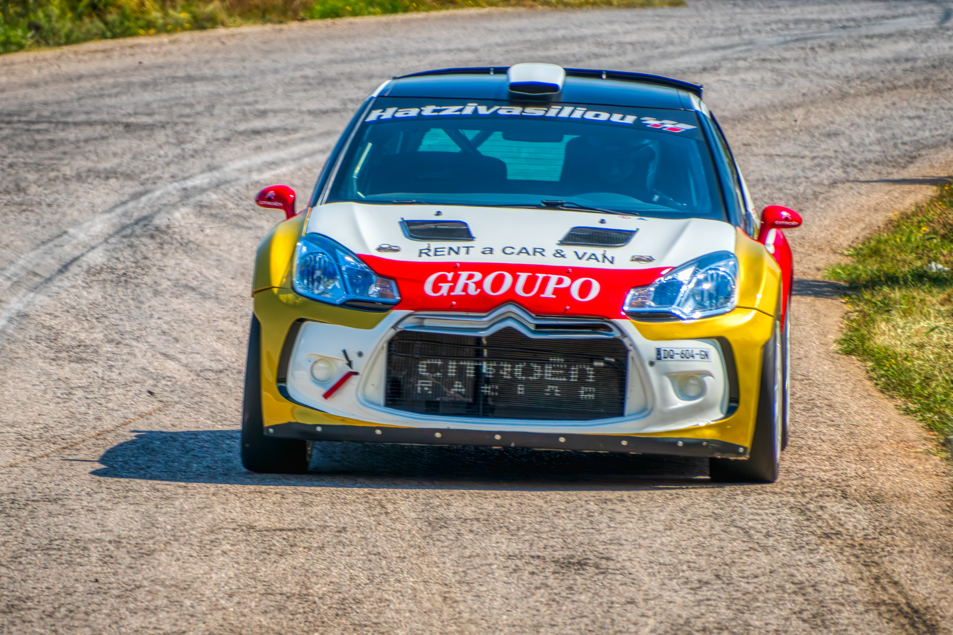 Exciting rally car racing on a road in Ritsona, Greece, with vibrant vehicle graphics.