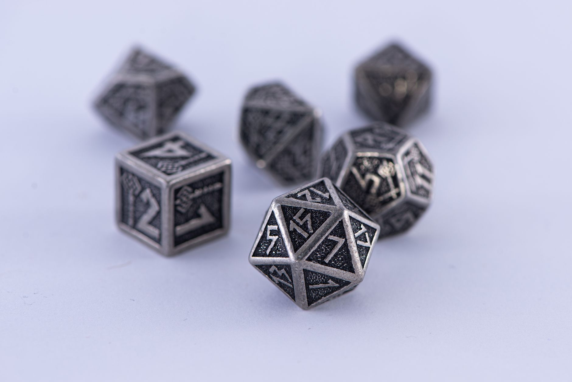 Metal polyhedral dice set displayed on a white surface. Perfect for tabletop gaming enthusiasts.