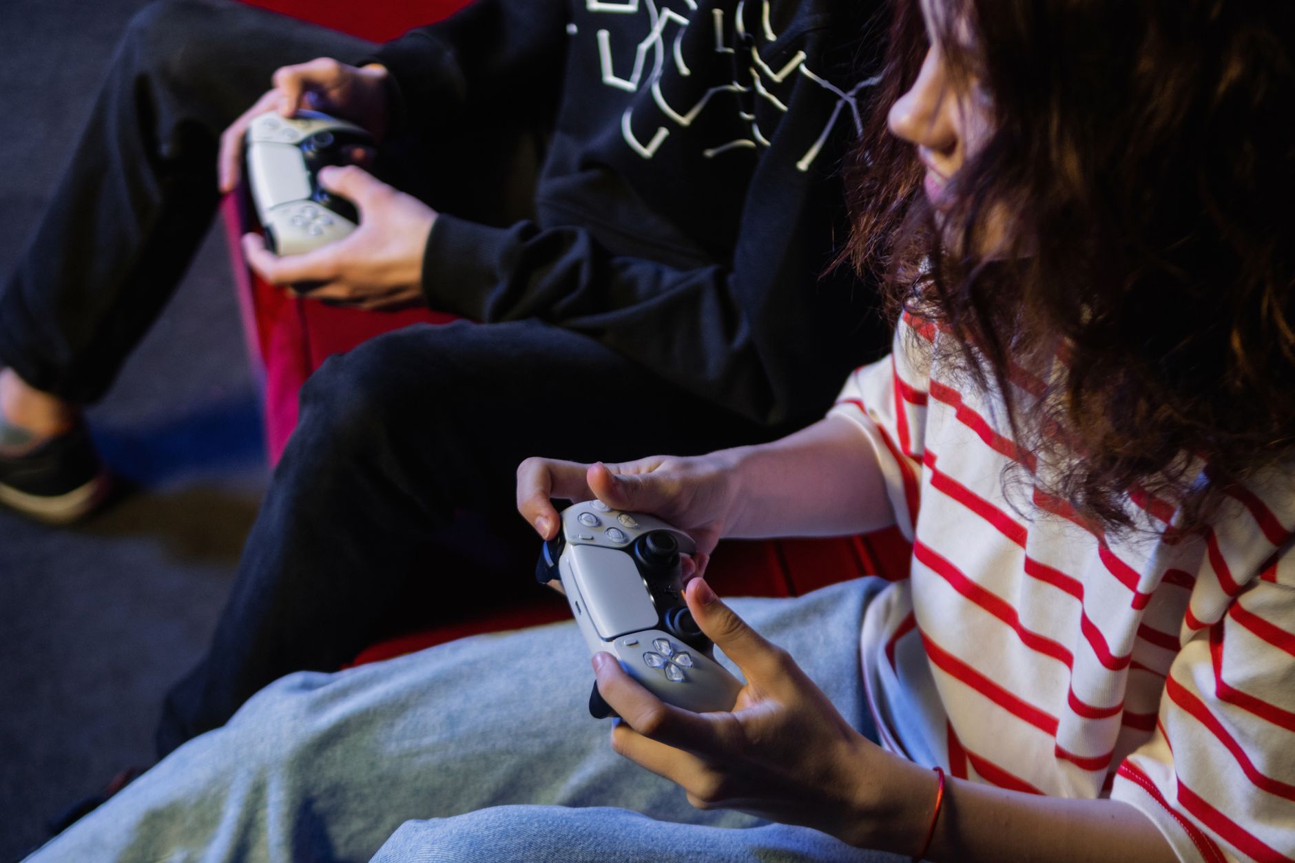 Two young gamers intensely focused while playing video games with modern controllers indoors.