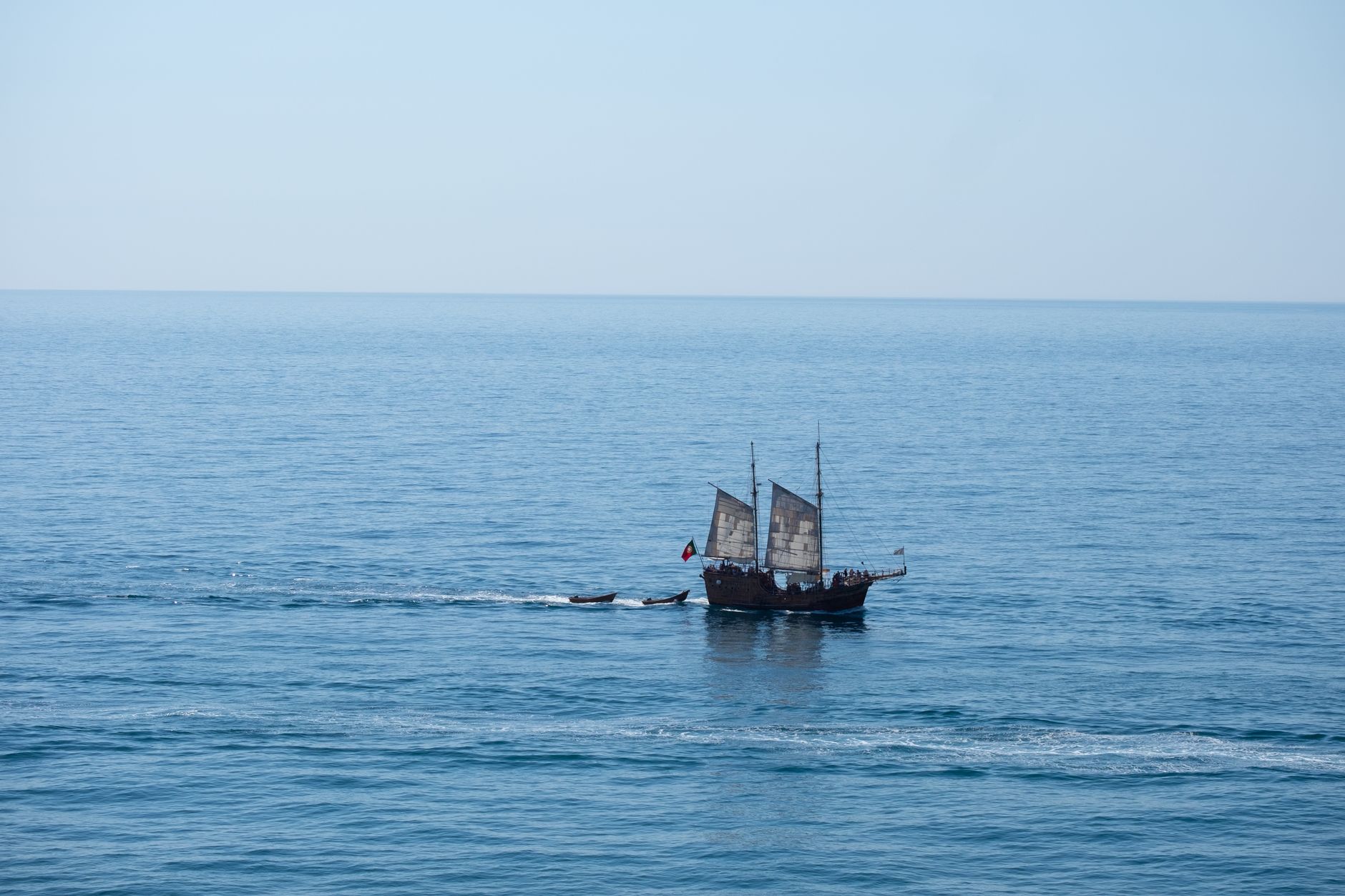A majestic pirate ship sails across the calm waters of the Algarve coast.