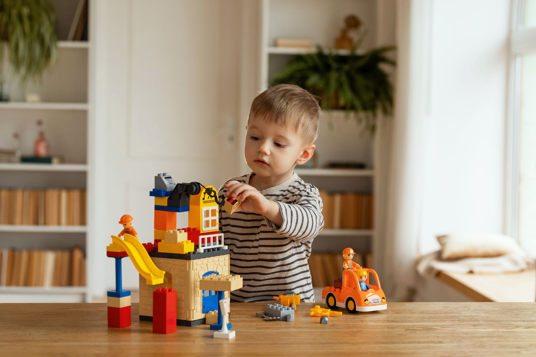 Young child playing creatively with building blocks indoors, fostering imagination and fun.