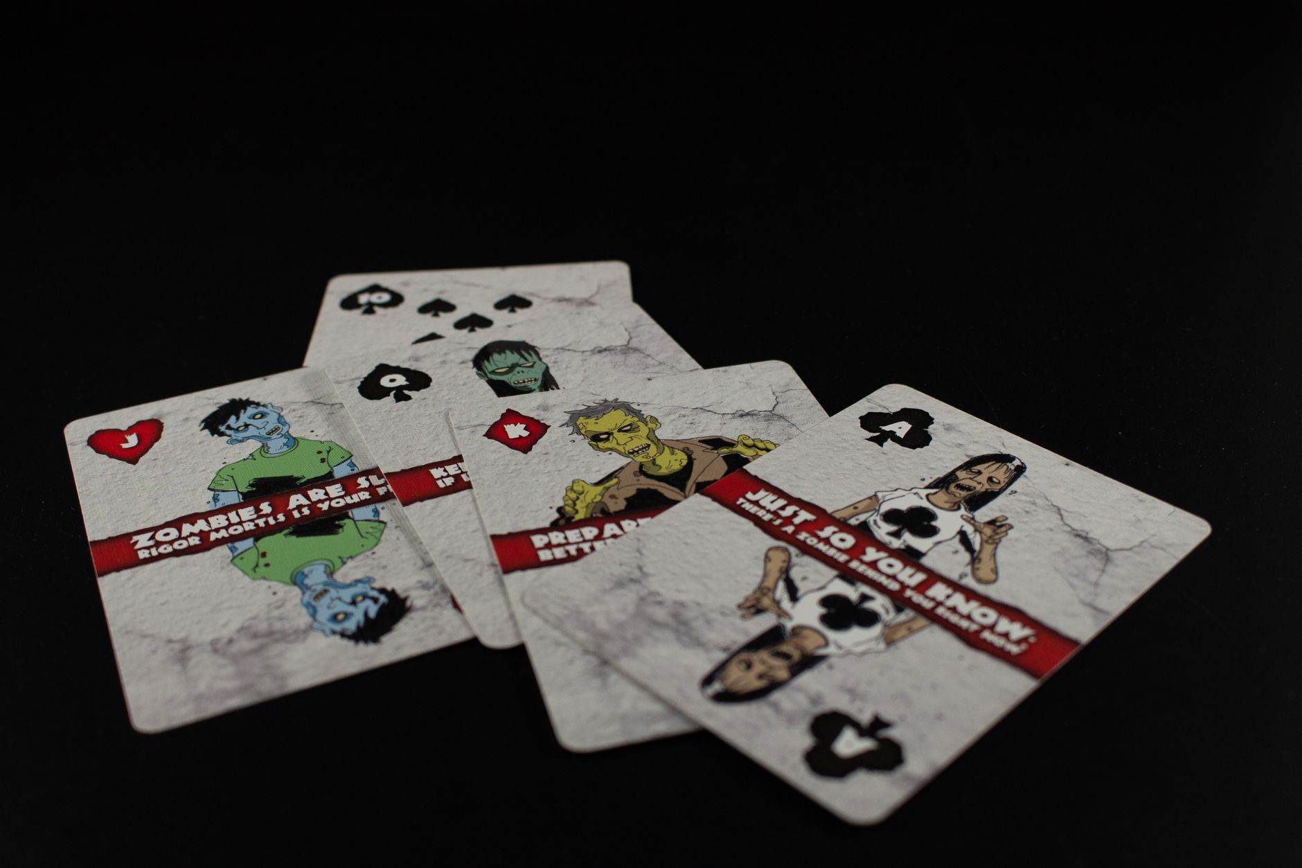 A dramatic still life of zombie-themed playing cards on a black background creates a spooky ambiance.