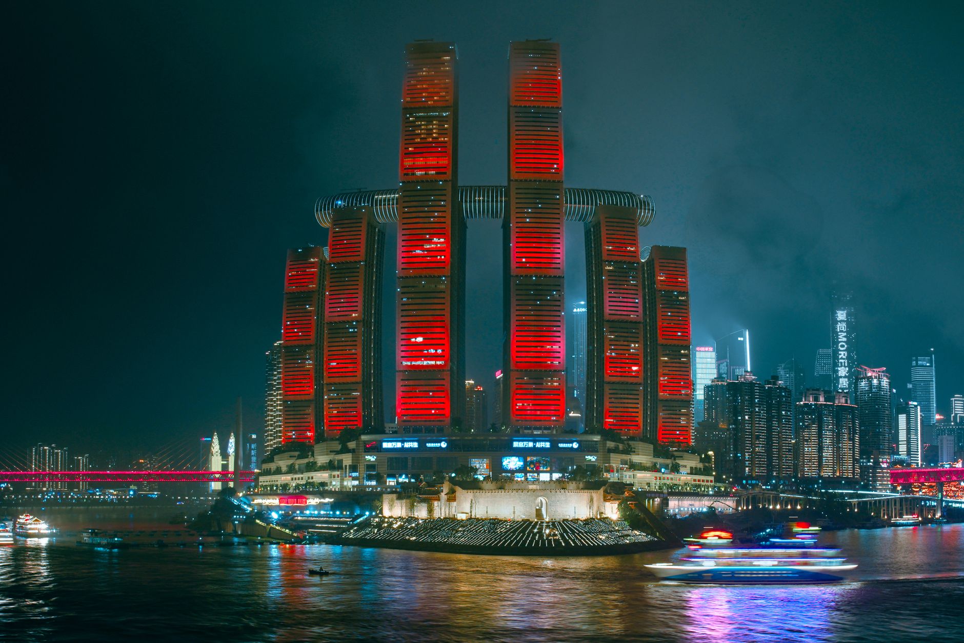 Illuminated skyscrapers reflecting in the river, showcasing Chongqing's modern cyberpunk skyline.