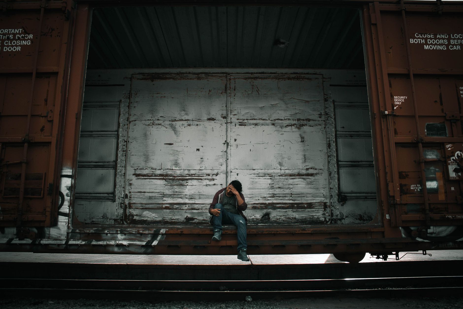 A man sitting on a rusty freight wagon, reflecting deeply.