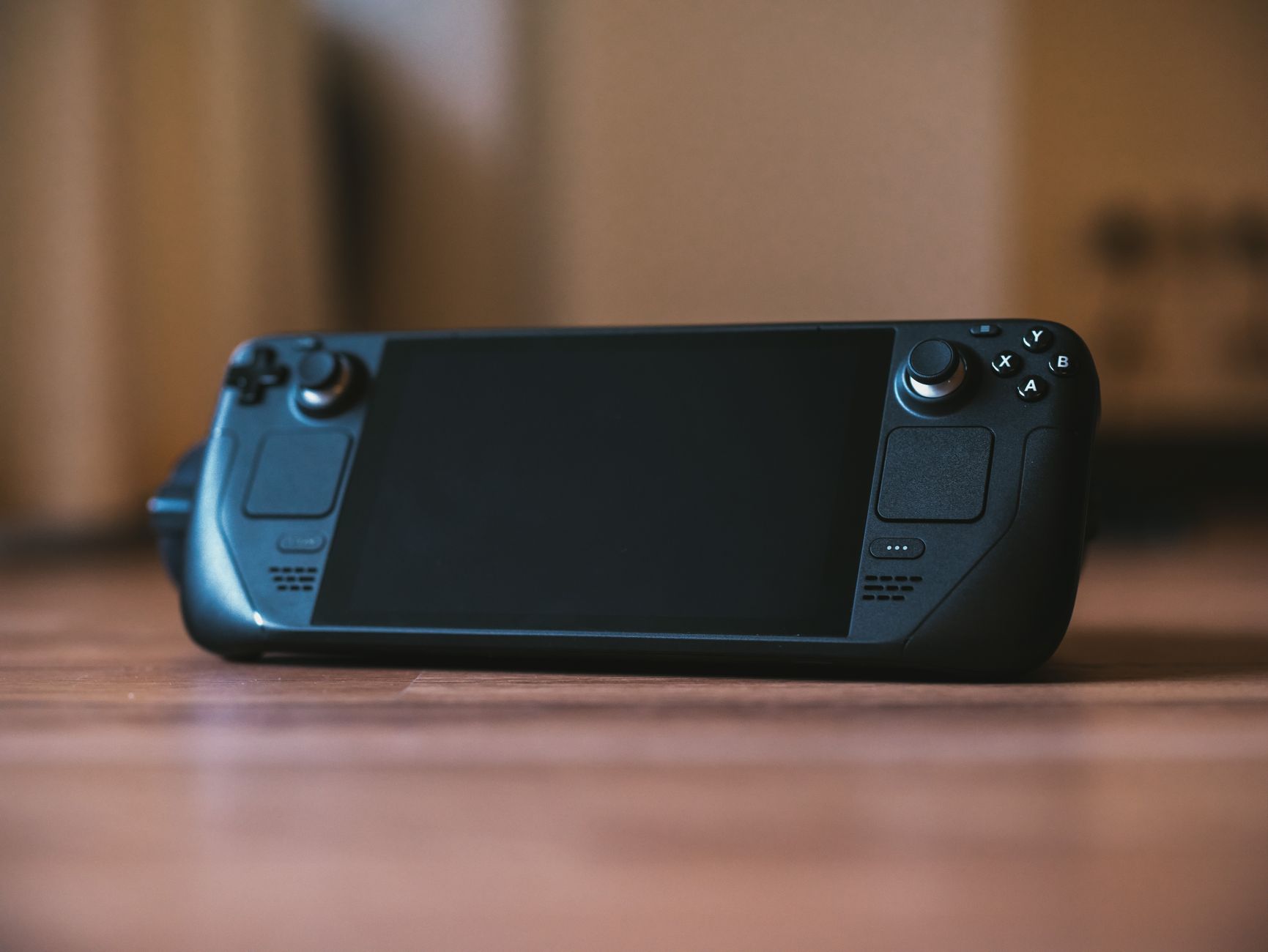 Modern handheld gaming console with buttons and joystick on a wooden surface, ideal for portable gaming enthusiasts.