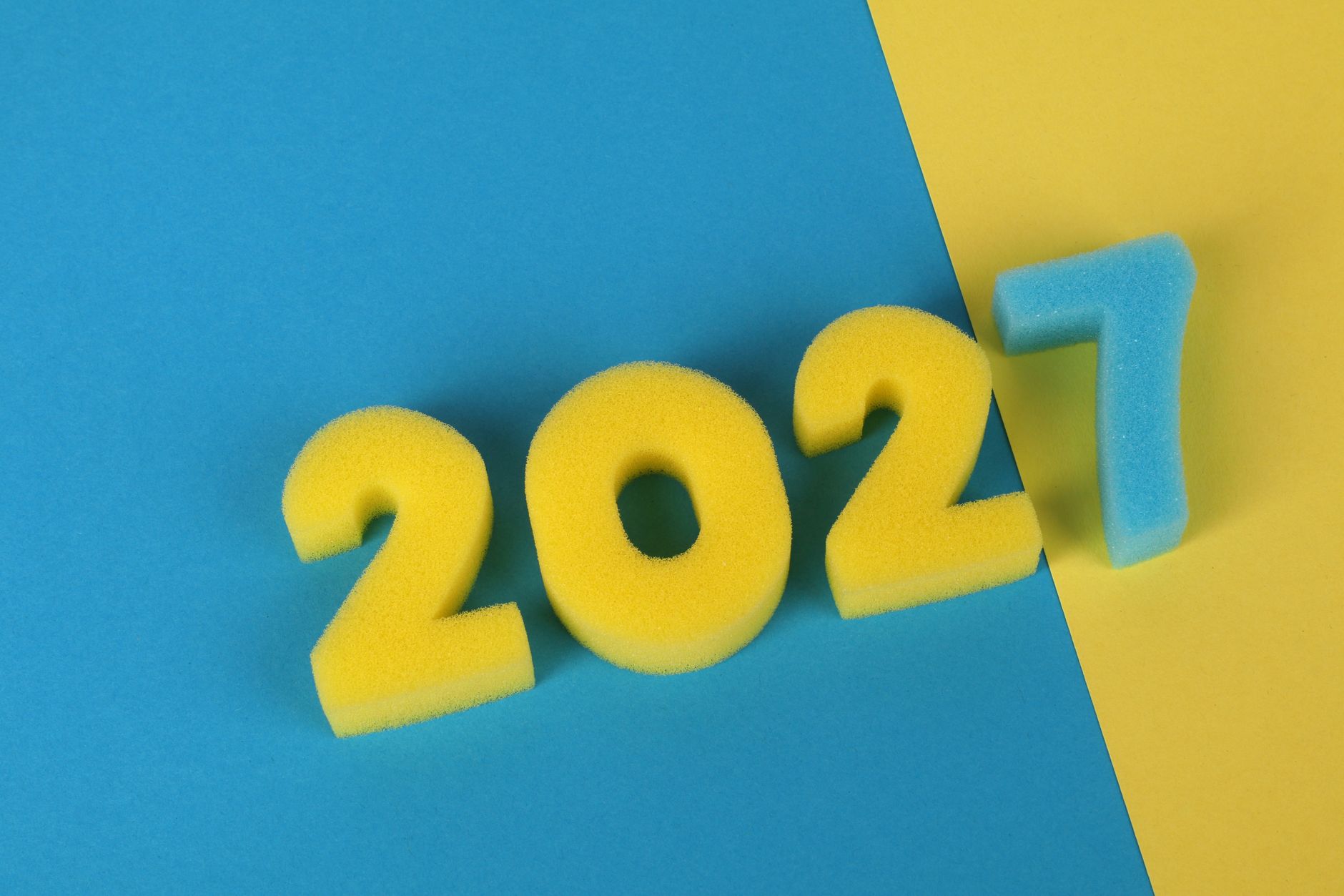 Yellow and blue foam numbers forming 2027 on vibrant blue and yellow background.