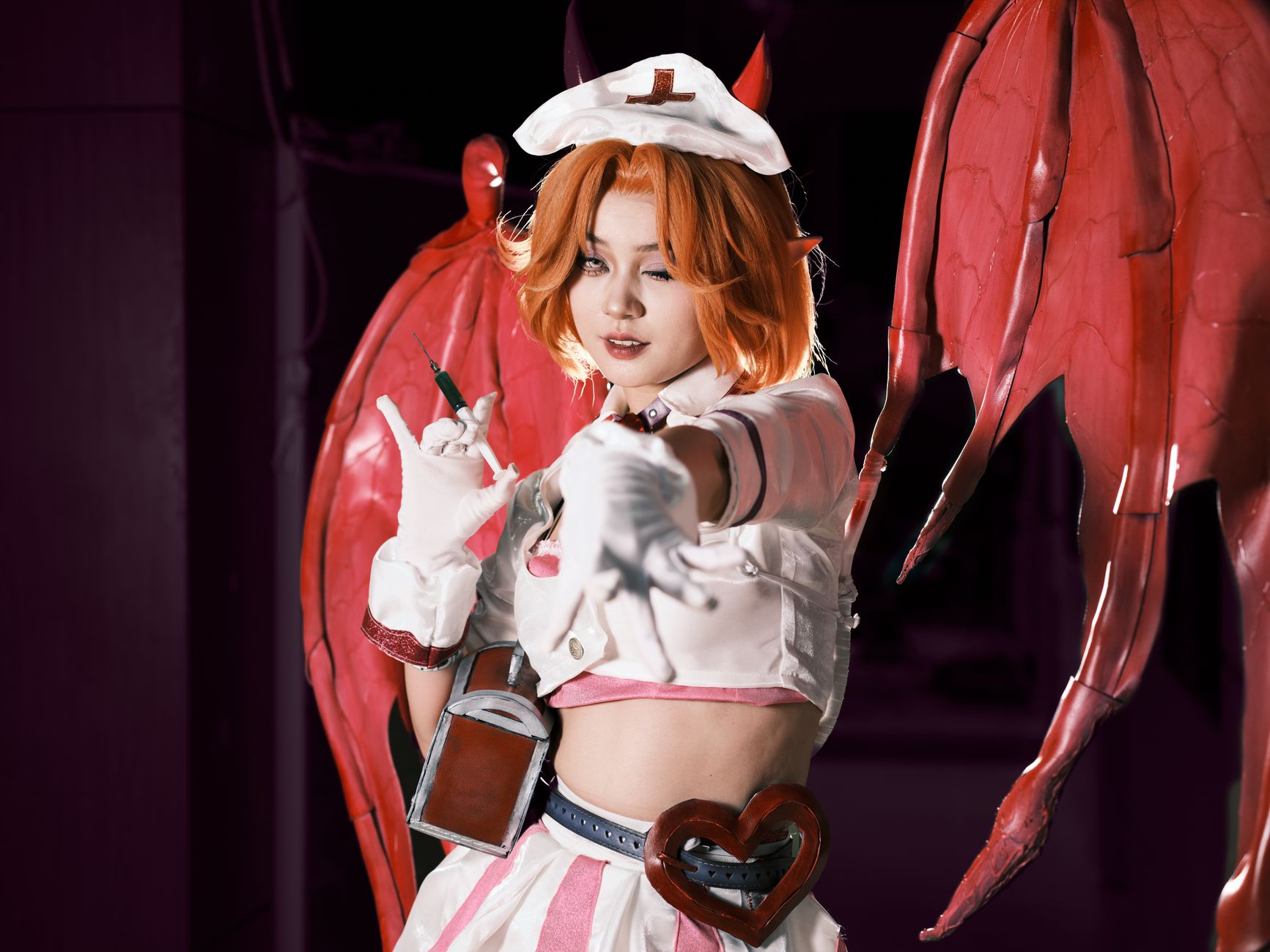 Cosplayer in a demon-themed costume with red wings, posing dramatically. Perfect for fantasy and cosplay themes.