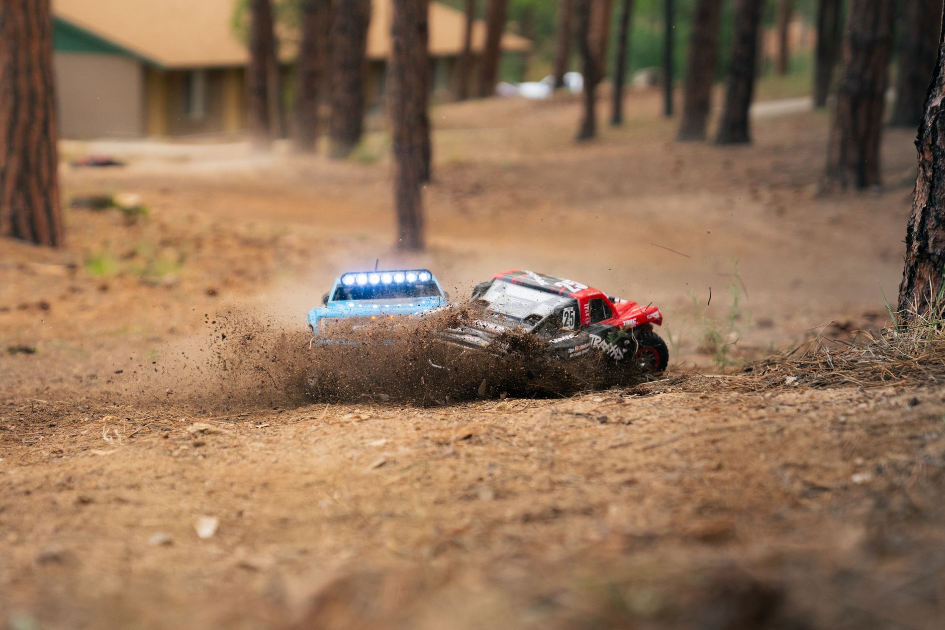 Two RC cars race through a forest, kicking up dirt in a display of speed and action.