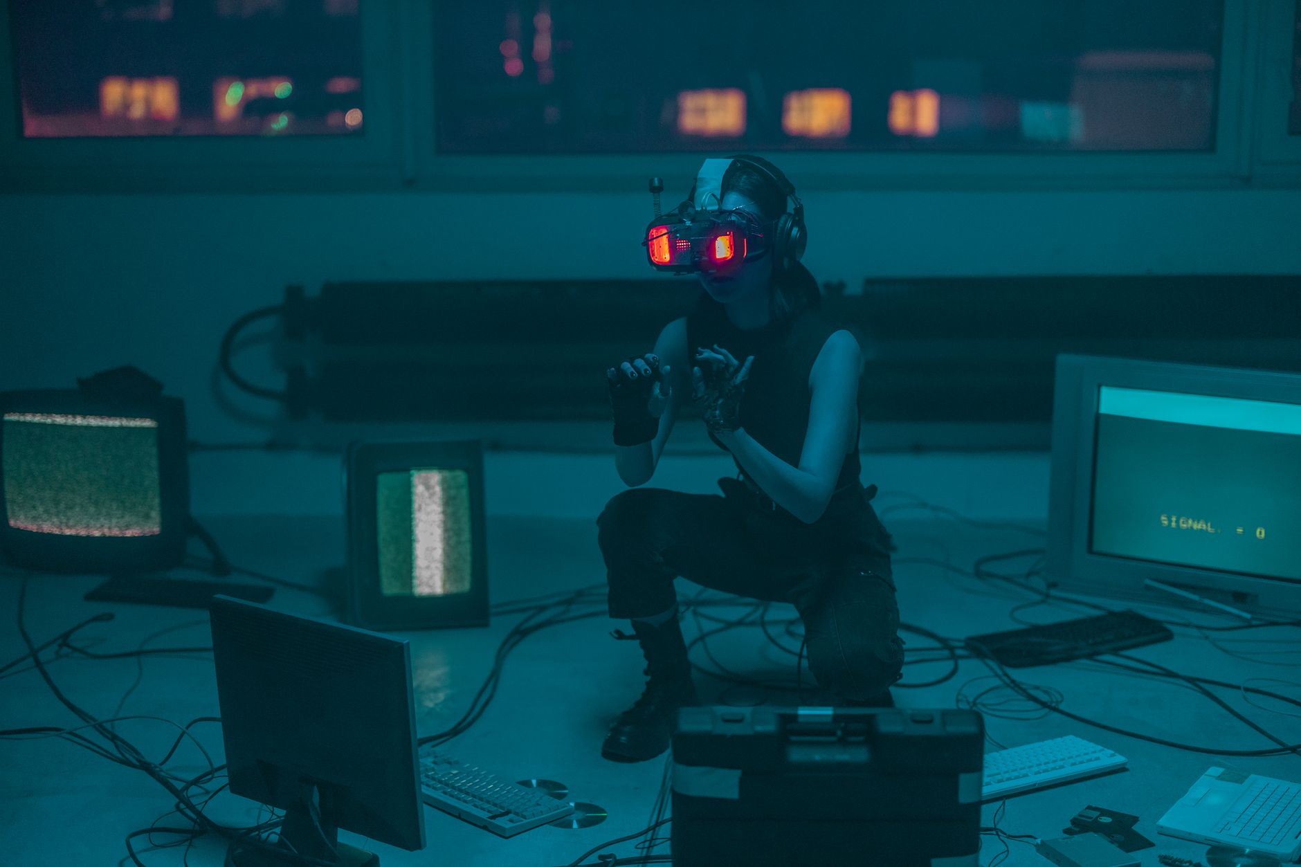 A woman crouching with VR headset in a sci-fi room filled with digital screens.