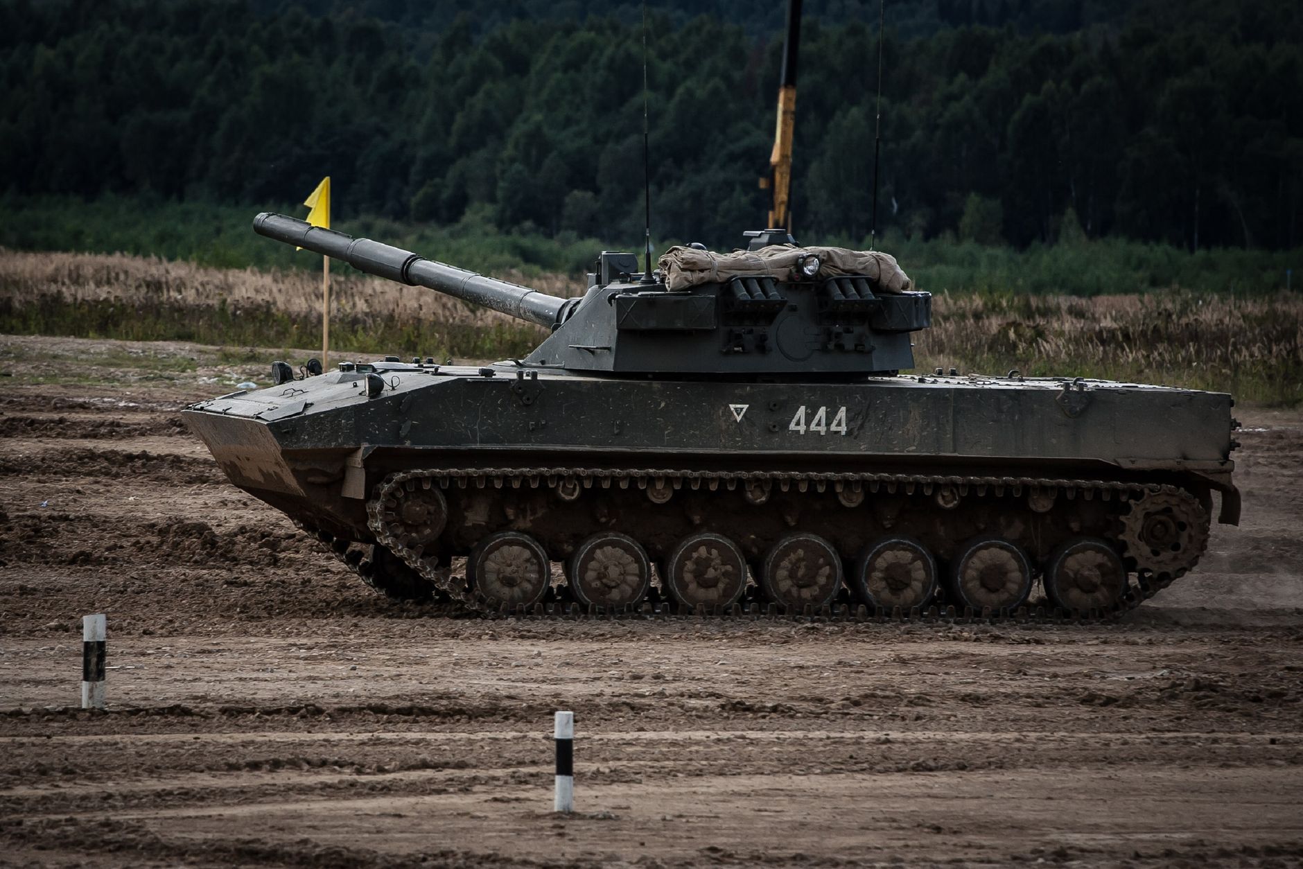 A military tank moves swiftly on a training ground, showcasing power and readiness.