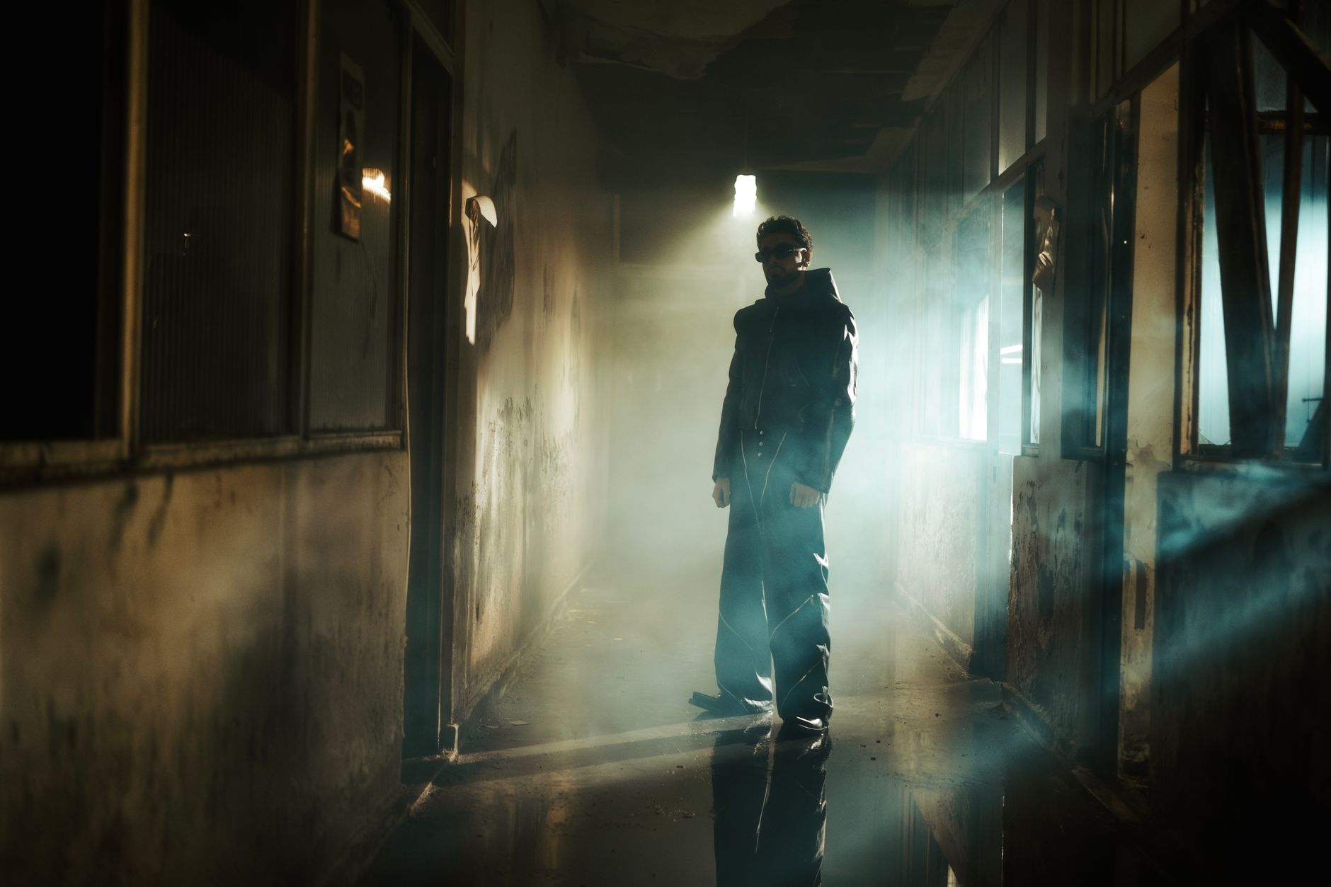 A man in dark attire stands in a smoky, shadowy corridor, creating a mysterious vibe.