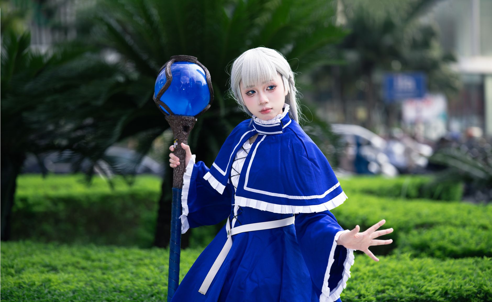 A person in a detailed fantasy costume holding a staff outdoors.