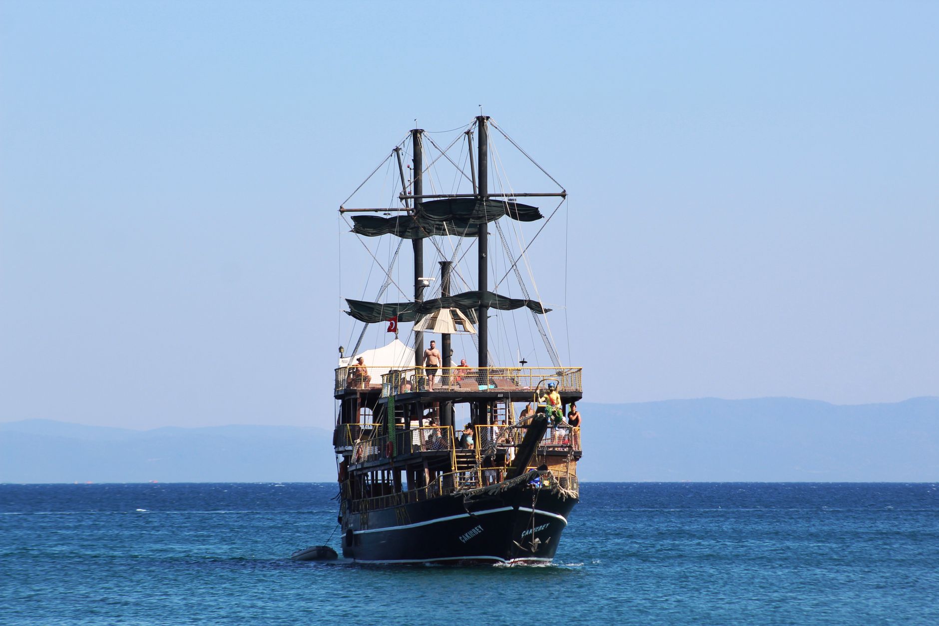Vintage pirate ship sailing on the turquoise ocean under a clear blue sky.