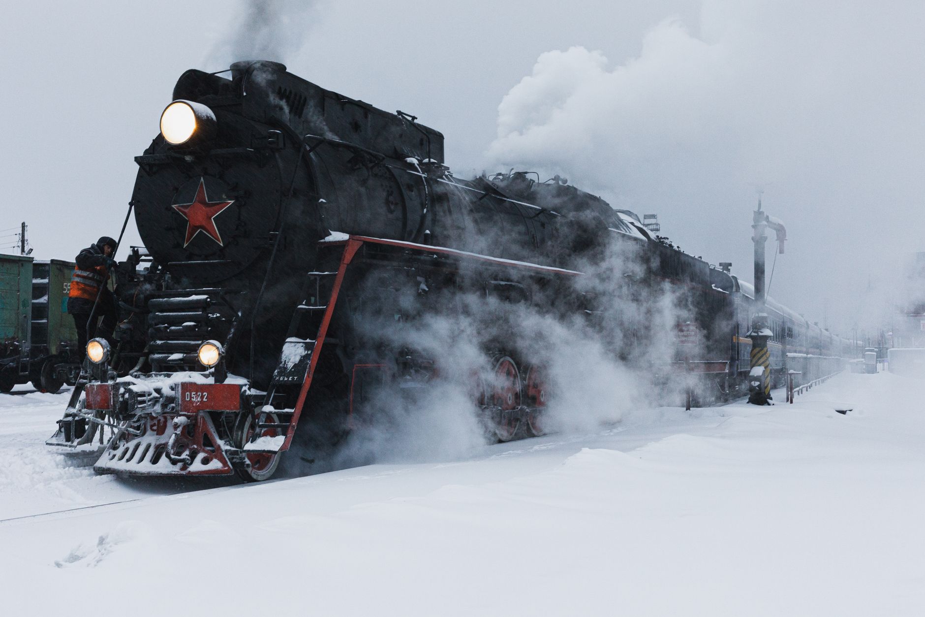 A classic steam locomotive moves through a snow-covered landscape, illustrating vintage travel.