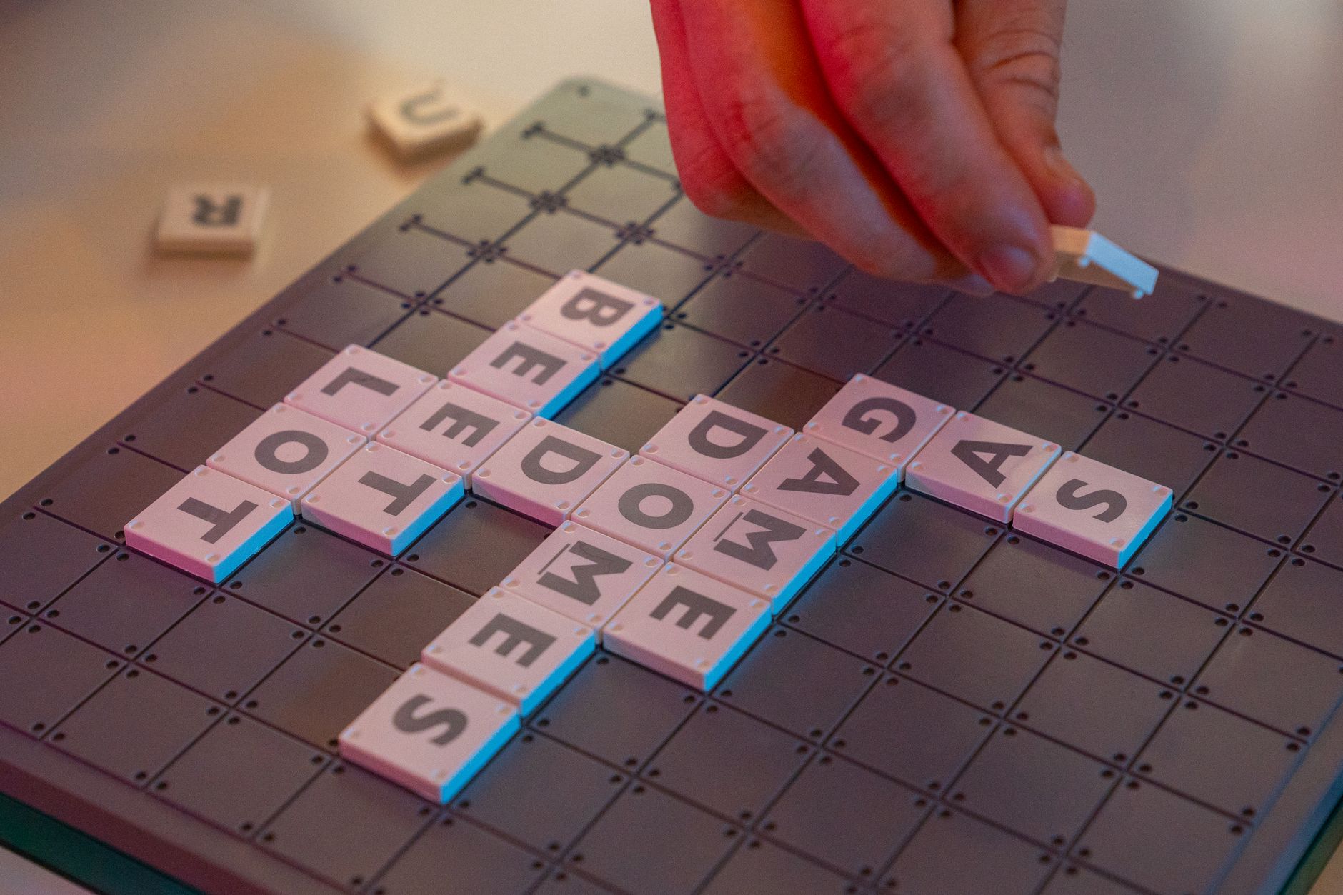 A close-up shot of a Scrabble game board with a hand placing tiles.