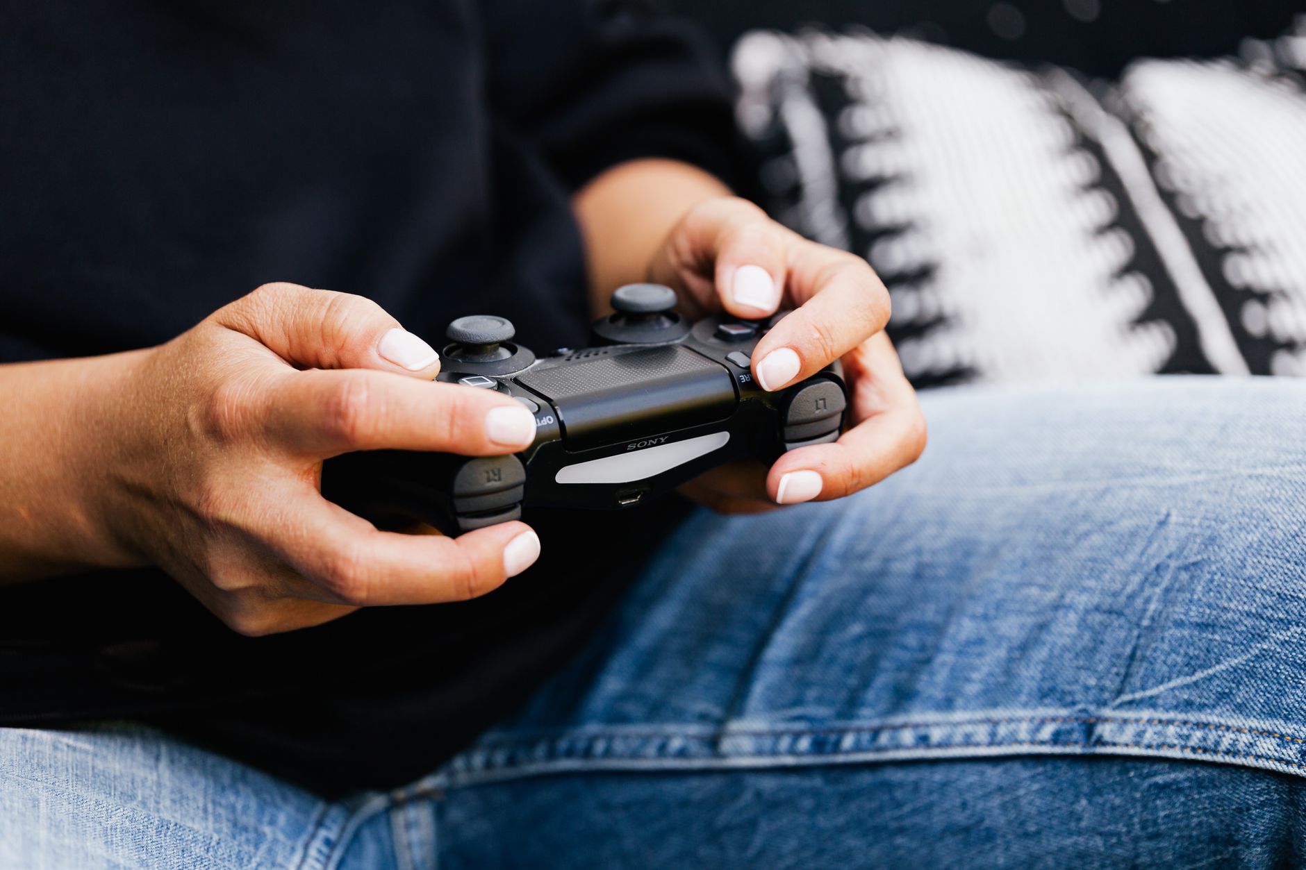 A person playing video games with a close-up of their hands holding a gaming controller.